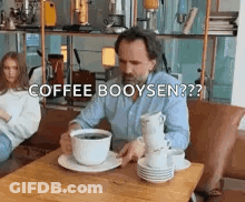 Man Sitting At Table With Stack Of Coffee Cups GIF