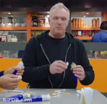 Man Sitting At Table With Toothpaste Tubes GIF