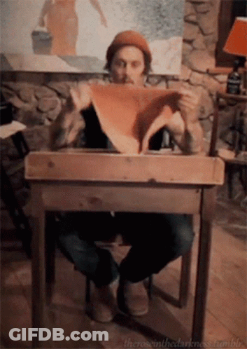 Man Sitting At Wooden Table Holding Paper GIF