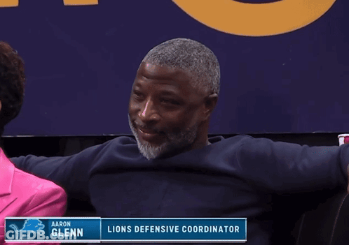 Man Sitting By Aaron Glenn Lions Defensive Coordinator Sign GIF