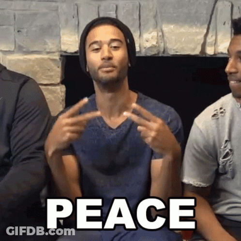 Man Sitting By Fireplace Making Peace Sign GIF