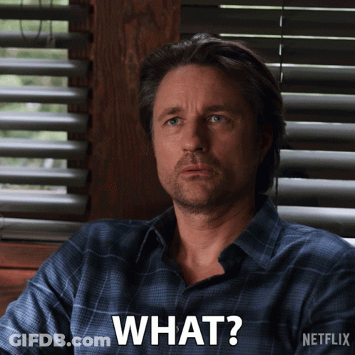 Man Sitting By Window With Blinds Saying What GIF