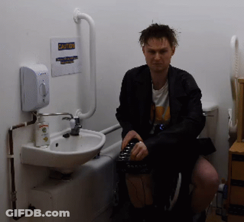 Man Sitting In Bathroom With Caution Sign GIF
