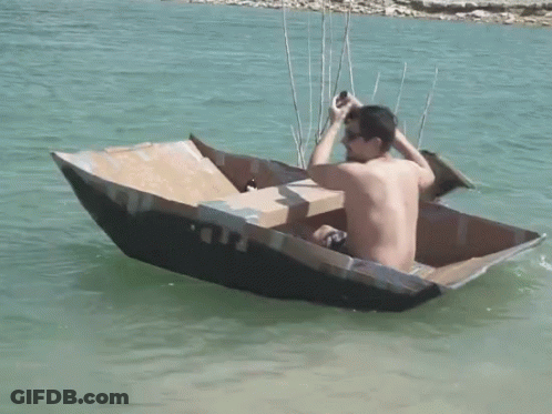 Man Sitting In Cardboard Boat With Beer GIF