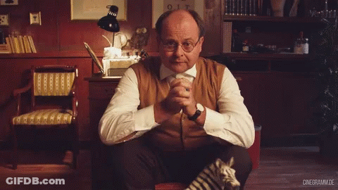 Man Sitting In Chair Hands Folded Bookshelf 012 Sign GIF