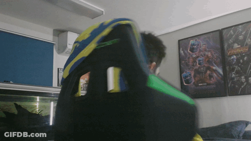 Man Sitting In Chair In Front Of Avengers Poster GIF