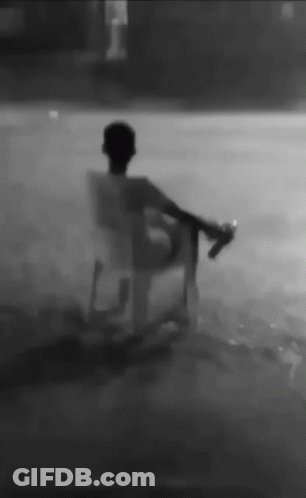 Man Sitting In Chair In Rain Holding Bottle GIF