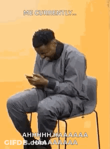 Man Sitting In Chair Looking At Phone GIF