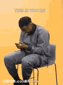 Man Sitting In Chair Looking At Phone GIF