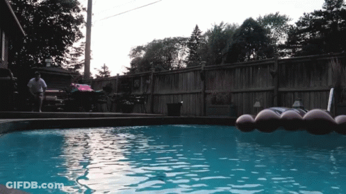 Man Sitting In Chair Next To Pool With Raft GIF