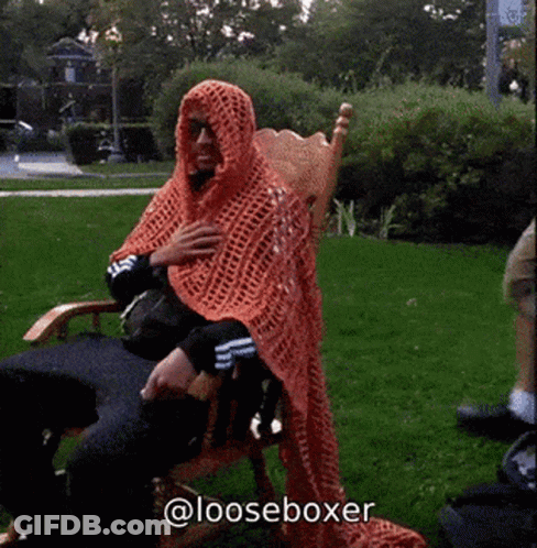 Man Sitting In Chair With Orange Blanket On Head And @Looseboxer GIF