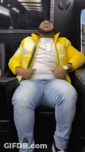 Man Sitting In Chair With Yellow Jacket And Blue Jeans GIF