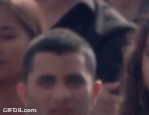 Man Sitting In Crowd Looking GIF