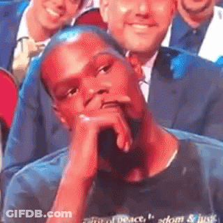 Man Sitting In Crowd With Chin On Hand GIF