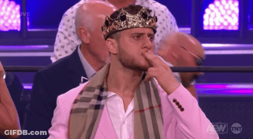 Man Sitting In Crown And Pink Suit At TNT Sign GIF