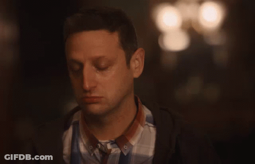 Man Sitting In Dark Room With Arm Around Shoulder GIF