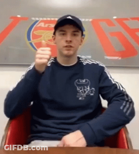 Man Sitting In Front Of Arsenal Sign GIF