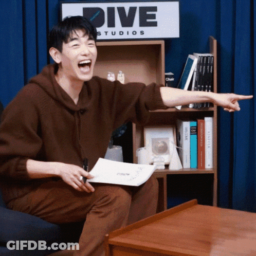 Man Sitting In Front Of Dive Studios Sign GIF