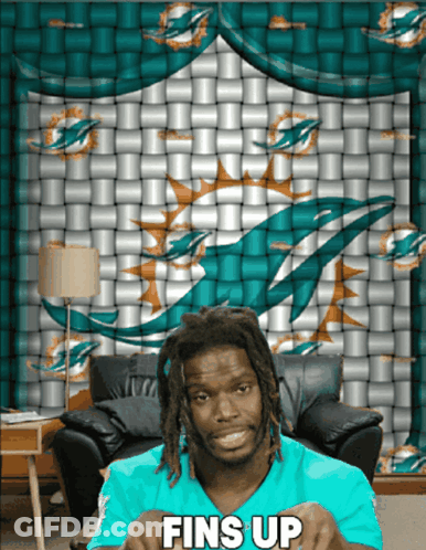 Man Sitting In Front Of Dolphin Wall Saying Fins Up GIF