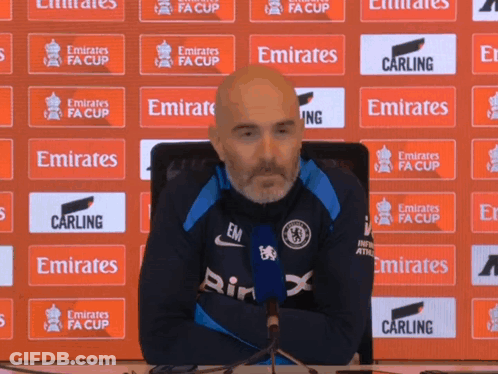 Man Sitting In Front Of Emirates FA Cup Banner GIF