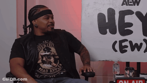 Man Sitting In Front Of Hey Crew Sign GIF