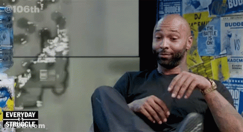Man Sitting In Front Of Posters Saying Everyday Struggle GIF