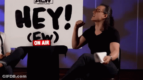 Man Sitting In Front Of Sign Saying Hey GIF