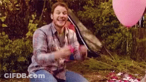 Man Sitting In Woods With Pink Balloons And Tent GIF