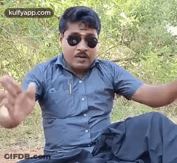 Man Sitting In Woods With Sunglasses And Blue Shirt GIF