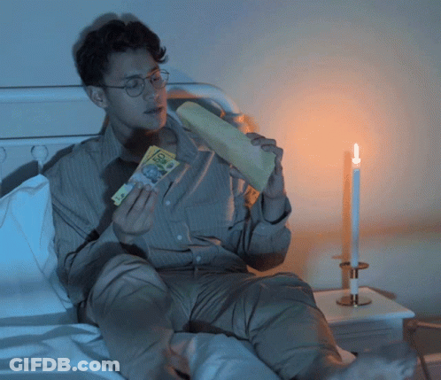 Man Sitting On Bed Holding Paper Saying 50 GIF