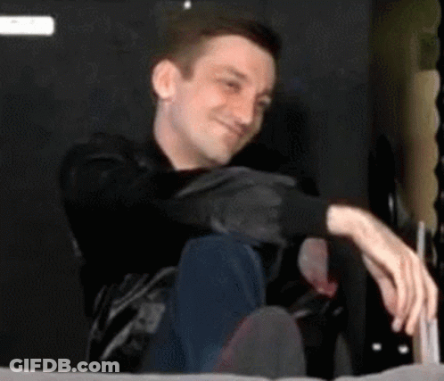 Man Sitting On Bed With Crossed Legs Smiling GIF