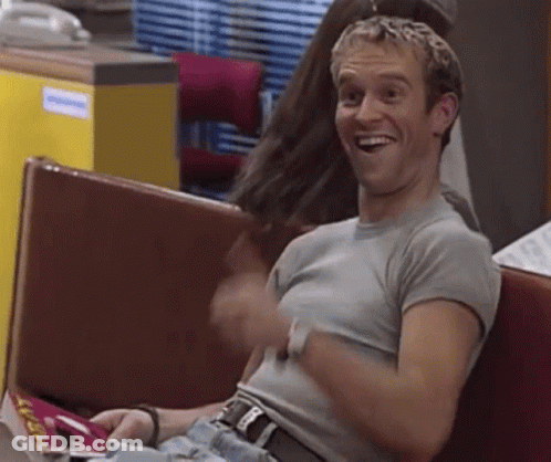 Man Sitting On Bench In Restaurant Laughing Holding Magazine GIF