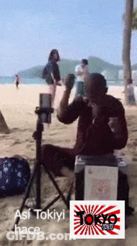 Man Sitting On Box On Beach With Tokyo Logo GIF