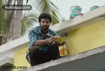 Man Sitting On Building Edge Holding Paint Bucket And Brush GIF