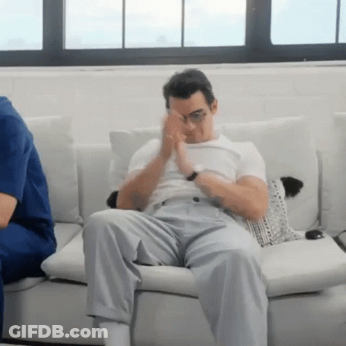 Man Sitting On Couch Covering Eyes GIF