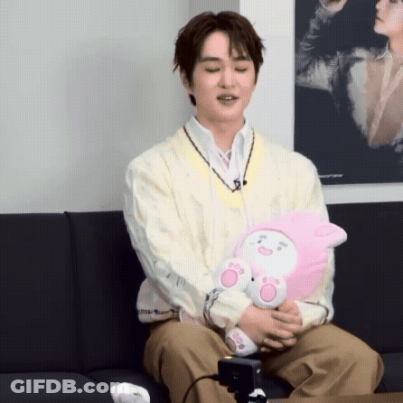 Man Sitting On Couch Holding Stuffed Animal GIF