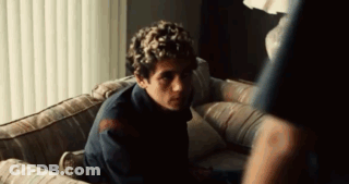 Man Sitting On Couch In Dark Room Looking At Something GIF