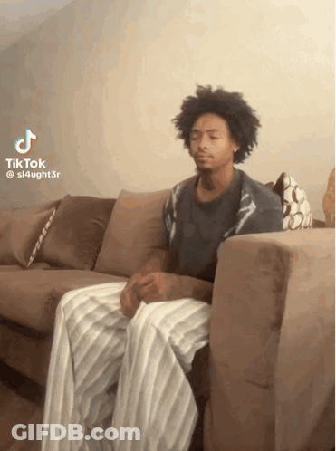 Man Sitting On Couch Legs Crossed Looking At Camera GIF