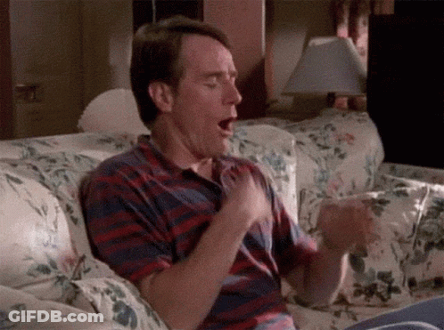 Man Sitting On Couch Mouth Open Hands On Chest GIF