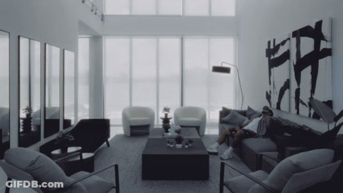Man Sitting On Couch With Chairs And Coffee Table GIF