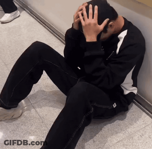 Man Sitting On Floor With Hand On Head GIF