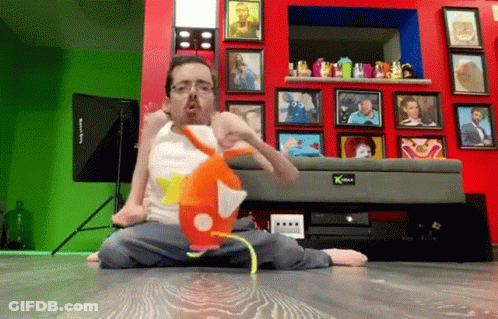 Man Sitting On Floor With Stuffed Animal In Front Of Picture Wall GIF