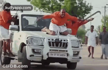 Man Sitting On Front Of Car With Group Standing Around GIF