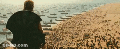 Man Sitting On Hill Overlooking Boats And Soldiers GIF