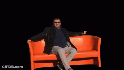 Man Sitting On Orange Couch In Front Of Explosion GIF