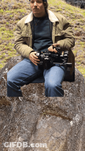 Man Sitting On Rock Holding Camera GIF