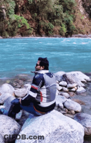 Man Sitting On Rock Near River GIF