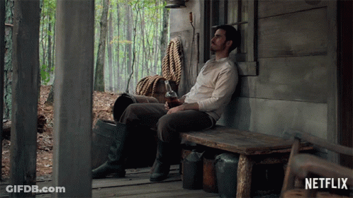 Man Sitting On Wooden Bench In Front Of Netflix Sign GIF