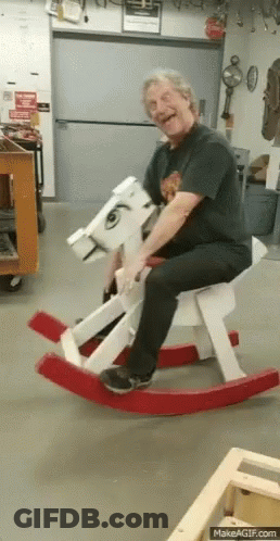 Man Sitting On Wooden Rocking Horse Smiling GIF