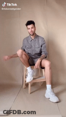 Man Sitting On Wooden Stool With Legs Crossed TikTok GIF